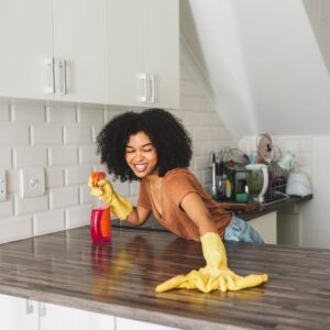 A woman wiping down a kitchen counter 
