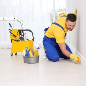 Housekeeping Man scrubbing floor boards with a sponge. 
