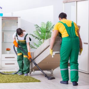Housekeeping Service team lifting up a couch to vacuum underneath it. 